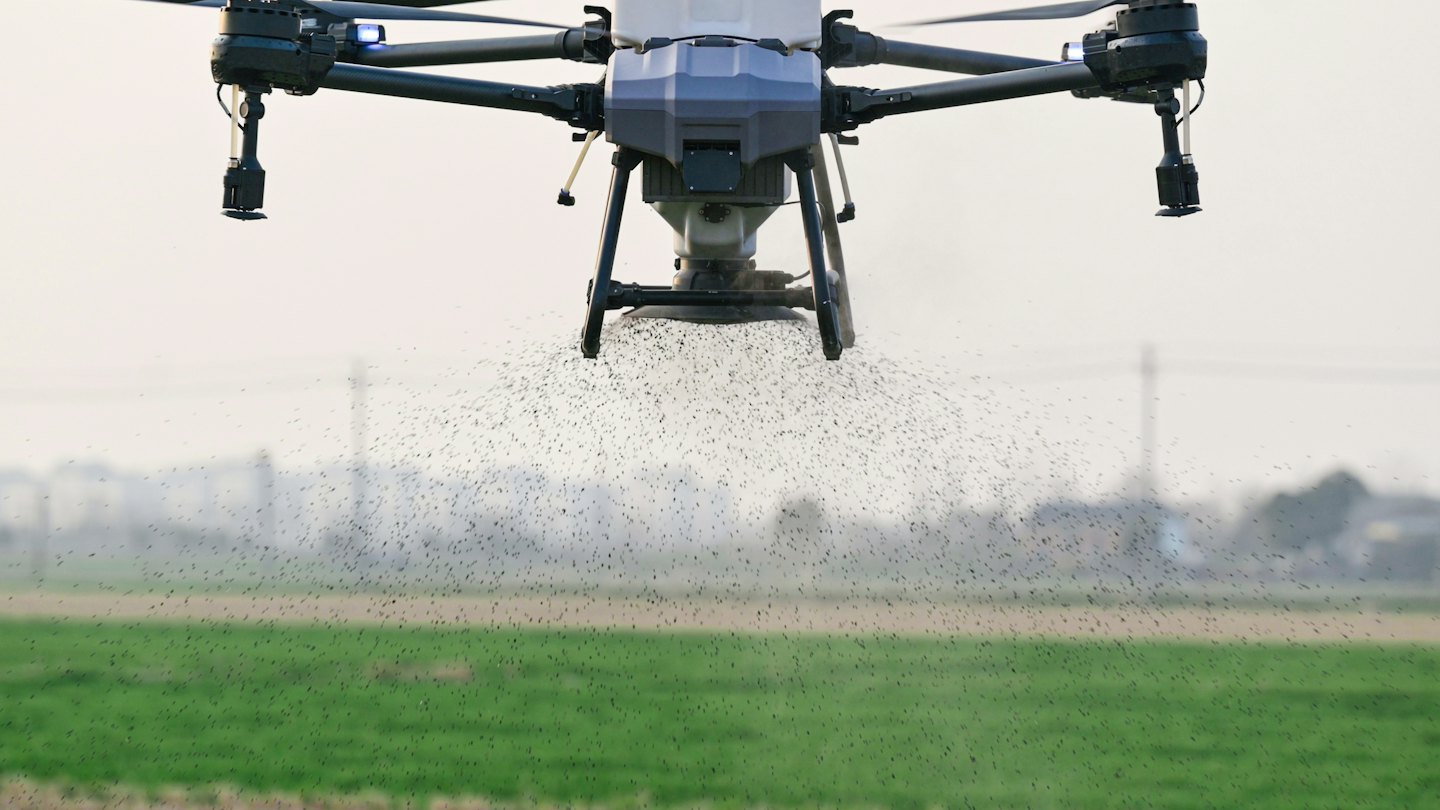 Drone agricolo che spruzza un campo dall'alto.